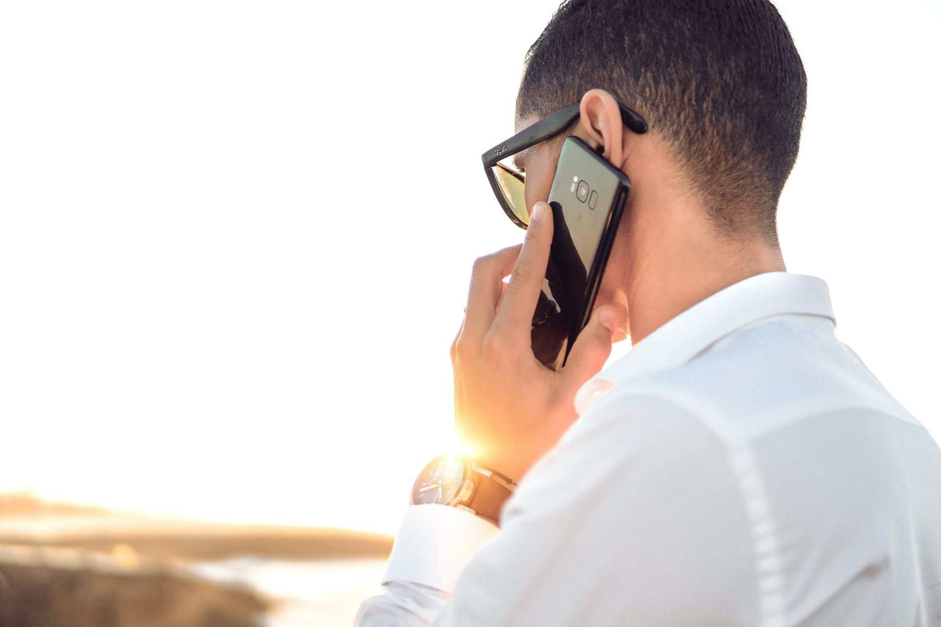 A person facing away, holding a mobile phone to their ear